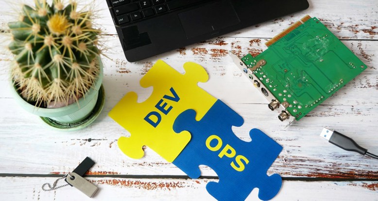 Photograph of a desk with assorted objects including two connected jigsaw pieces with the words dev and ops