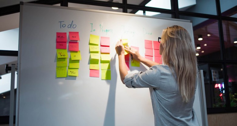 Photograph of someone adding a sticky note to a workshop whiteboard